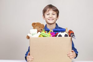 Young boy holding box of toys to be donated 