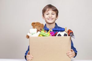 A boy holding a box with toys peeking out of the top