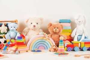 Educational kids toys collection. Teddy bear, wood plane, train, abacus, rainbow, and other toys neatly stacked for donation